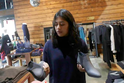 In this Feb. 15, 2018 photo, Ayesha Tellis holds up shoes she designed on her computer at a Betabrand store in San Francisco. Betabrand represents one of the most dramatic examples of how companies _ big and small _ are starting to use digital technology to reinvent and speed up the process of designing and selling clothing to shoppers in the age of Amazon.