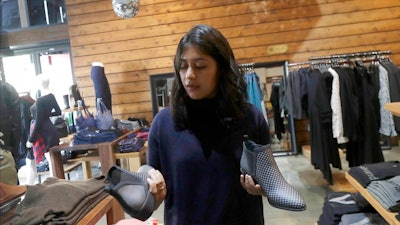 In this Feb. 15, 2018 photo, Ayesha Tellis holds up shoes she designed on her computer at a Betabrand store in San Francisco. Betabrand represents one of the most dramatic examples of how companies _ big and small _ are starting to use digital technology to reinvent and speed up the process of designing and selling clothing to shoppers in the age of Amazon.