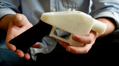 In this May 10, 2013, file photo, Cody Wilson holds what he calls a Liberator pistol that was completely made on a 3-D-printer at his home in Austin, Texas. Eight states filed suit Monday, July 30, 2018, against the Trump administration over its decision to allow a Texas company to publish downloadable blueprints for a 3D-printed gun, contending the hard-to-trace plastic weapons are a boon to terrorists and criminals and threaten public safety.