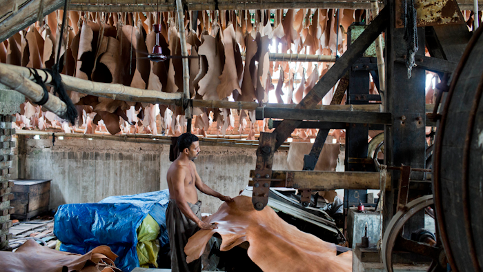 In this Thursday, June 28, 2018, photo, a Bangladeshi laborer processes leather at a factory on the banks of the Daleshwari River in Savar, Bangladesh. Bangladesh tanneries prepping leather for shoes, belts, wallets and purses are dumping toxic chemicals into the Daleshwari river at a new industrial complex more than a year after the government shut them down for poisoning a different river and using child labor.