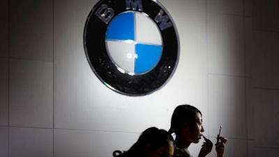 In this file photo dated Friday, Sept. 25, 2015, Models prepare to work at the BMW booth during the Imported Auto Expo in Beijing, China. Automaker BMW said Monday July 9, 2018, it will have to raise prices on the U.S.-built SUVs it sells in China due to 40 percent import tax on cars from the United States, in retaliation for higher tariffs on Chinese goods imposed by President Donald Trump.