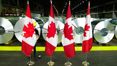 A member of the A/V team straightens Canadian flags in front of rolls of coated steel at Stelco in Hamilton before a visit by Chrystia Freeland, Minister of Foreign Affairs, spoke, Friday, June 29, 2018. Canada announced billions of dollars in retaliatory tariffs against the U.S. on Friday in a tit for tat response to the Trump administration's duties on Canadian steel and aluminum.
