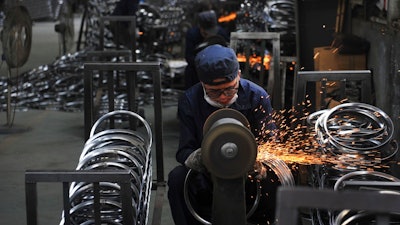 In this June 4, 2018, photo, a worker wields steel wheel rims at a factory in Hangzhou in east China's Zhejiang province. China launched a trade investigation Monday, July 23, 2018 of steel from Europe and South Korea, potentially complicating efforts to recruit them as allies in its tariff dispute with U.S. President Donald Trump.
