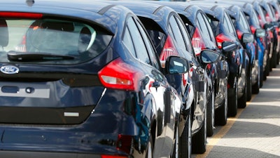 In this Friday, July 21, 2017, file photo, Ford cars wait for deployment after arrival by ship at the Ford Dagenham diesel engine plant in London. An escalating trade war and steep tariffs on steel and aluminum are putting pressure on earnings for automakers, prompting General Motors to slash its outlook while also weighing down shares of Ford Motor Co. and auto parts companies.
