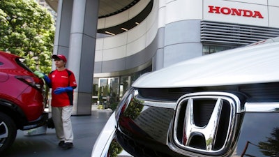 An employee of Honda Motor Co. cleans a Honda car displayed at its headquarters in Tokyo, Tuesday, July 31, 2018. Honda profits jumped 17.8 percent in the latest quarter, driven by strong auto sales in North America and motorcycle sales in Asia, the company said Tuesday.