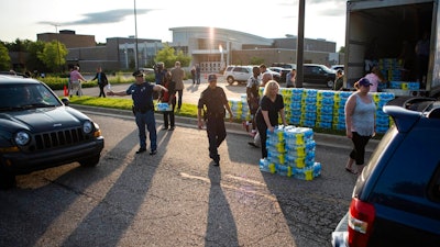 Emergency response teams hand out free bottled water to residents at the Parchment High School in Parchment, Mich., Friday, July 27, 2018. Authorities handed out thousands of free bottles of water Friday for two southwestern Michigan communities where the discovery of contamination from toxic industrial chemicals prompted a warning against using the public water system for drinking or cooking.