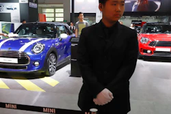 In this April 26, 2018, photo, a security guard stands near MINI cars displayed at the China Auto Show in Beijing. BMW Group and China's biggest SUV brand, Great Wall Motor, announced Tuesday, July 10, 2018, a partnership to produce electric MINI vehicles in China.