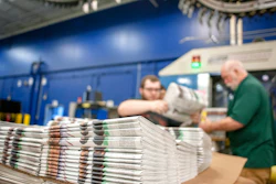 In this April 11, 2018, photo, production workers stack newspapers onto a cart at the Janesville Gazette Printing & Distribution plant in Janesville, Wis. Members of Congress are warning that newspapers in their home states are in danger of cutting coverage or going out of business if the United States maintains recently imposed tariffs on Canadian newsprint.