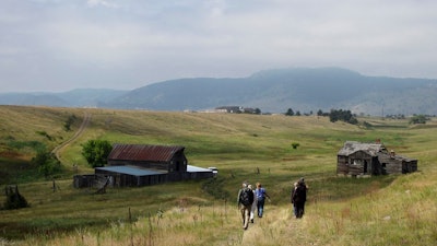 -In this Aug. 11, 2017 file photo, visitors approach a former ranch house and barn during a guided hike on the Rocky Flats National Wildlife Refuge near Denver, land that used to be a buffer zone around a nuclear weapons plant. Environmentalists and community activists are trying to stop the refuge from opening to the public this summer, claiming the U.S. Fish and Wildlife Service did not adequately study the safety of the site.