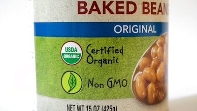In this Monday, July 9, 2018 photo a 'USDA Organic' label is printed on the label of a can of baked beans, in Walpole, Mass. The USDA Organic label generally signifies a product is made without synthetic pesticides and fertilizers, and that animals are raised according to certain standards. But disputes over the rules and reports of fraud may have some questioning whether the seal is worth the price.