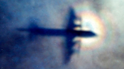 In this March 31, 2014 file photo, the shadow of a Royal New Zealand Air Force P3 Orion is seen on low level cloud while the aircraft searches for missing Malaysia Airlines Flight MH370 in the southern Indian Ocean, near the coast of Western Australia. An independent investigation report released Monday, July 30, 2018, more than four years after Malaysia Airlines Flight 370 disappeared highlighted shortcomings in the government response that exacerbated the mystery.