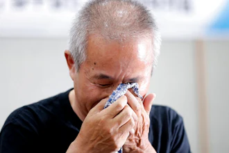 Hwang Sang-gi, father of former Samsung semiconductor factory worker Hwang Yu-mi who died from leukemia in 2007, wipes his tear during a signing ceremony in Seoul, South Korea, Tuesday, July 24, 2018. Samsung Electronics and a group representing ailing Samsung computer chip and display factory workers say they have agreed to end a years-long standoff over compensation for deaths and grave illnesses among Samsung workers.