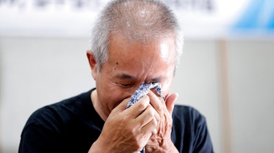 Hwang Sang-gi, father of former Samsung semiconductor factory worker Hwang Yu-mi who died from leukemia in 2007, wipes his tear during a signing ceremony in Seoul, South Korea, Tuesday, July 24, 2018. Samsung Electronics and a group representing ailing Samsung computer chip and display factory workers say they have agreed to end a years-long standoff over compensation for deaths and grave illnesses among Samsung workers.