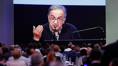 In this June 1, 2018, file photo, journalists watch a giant screen as Fiat Chrysler CEO Sergio Marchionne speaks during the 'Capital market day' at the FCA headquarters in Balocco, Italy. Fiat Chrysler’s late founding CEO Sergio Marchionne was a notorious workaholic who regularly slept on a corporate jet all the while landing in headlines for his shrewd deal-making. Despite his public profile, he kept a secret even from his board: he’d been seriously ill for more than a year.