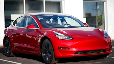 In this May 27, 2018, file photo, a 2018 Model 3 sedan sits at a Tesla dealership in Littleton, Colo. Tesla Inc. made 5,031 lower-priced Model 3 electric cars during the last week of June, surpassing its often-missed goal of 5,000 per week. Tesla reported making 28,578 Model 3s from April through June, according to its quarterly production release on Monday, July 2.