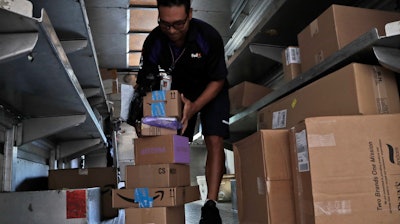 In this Tuesday, July 17, 2018 photo, a FedEx employee delivers packages in Miami. Amazon Prime Day was launched July 16 and and will be six hours longer than last year's and will launch new products.