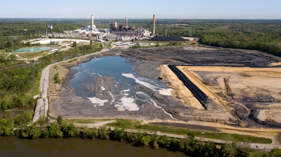 In this May 1, 2018 file photo, the Richmond city skyline can be seen on the horizon behind the coal ash ponds along the James River near Dominion Energy's Chesterfield Power Station in Chester, Va. The Trump administration is easing rules for handling toxic coal ash from more than 400 coal-fired power plants across the U.S. after utilities objected to regulations adopted under former President Barack Obama. Environmental Protection Agency acting Administrator Andrew Wheeler said Wednesday, July 18, 2018, the changes will save utilities roughly $30 million annually.