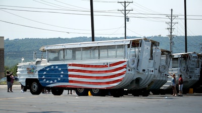 People view a row of idled duck boats in the parking lot of Ride the Ducks Saturday, July 21, 2018 in Branson, Mo. One of the company's duck boats capsized Thursday night resulting in several deaths on Table Rock Lake.