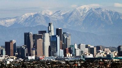 In this Dec. 31, 2014, file photo, the snow-capped San Gabriel Mountains provide a backdrop to the downtown Los Angeles skyline as seen from Kenneth Hahn State Recreation Area in Baldwin Hills. California greenhouse gas emissions fell below 1990 levels, meeting an early target years ahead of schedule and putting the state well on its way toward reaching long-term goals to fight climate change, officials said Wednesday, July 11, 2018.