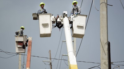 In this Oct. 19, 2017 file photo, a brigade from the Electric Power Authority repairs distribution lines damaged by Hurricane Maria in the Cantera community of San Juan, Puerto Rico. Jose Ortiz will take over Puerto Rico's Electric Power Authority on July 23, 2018, the company's second CEO in two weeks as it struggles with leadership issues, bankruptcy and the restoration of electricity to hundreds who have remained in the dark since Hurricane Maria.