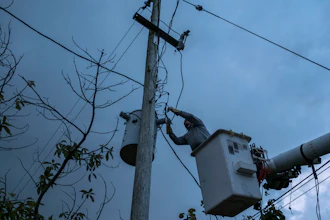 In this July 12, 2018 photo, a laborer from the Puerto Rico Power Authority works to restore power in Adjuntas, Puerto Rico. Puerto Rico's electrical grid is still shaky after Hurricane Irma brushed past the island as a Category 5 storm last Sept. 6 and then Hurricane Maria made a direct hit as a Category 4 storm two weeks later, damaging up to 75 percent of transmission lines.