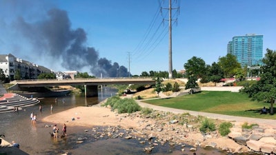 Firefighters are battling a large blaze at a metal recycling facility that sent up a large, black plume of smoke that could be seen for miles just north of downtown Denver, Tuesday, July 10, 2018. Fire crews from Denver and Adams County responded to the fire, which was reported at EVRAZ Recycling on Tuesday afternoon.