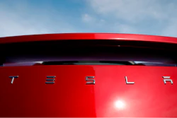 In this April 15, 2018, file photo, the sun shines off the rear deck of a roadster on a Tesla dealer's lot in the south Denver suburb of Littleton, Colo. Electric car producer Tesla says it will build its first factory outside the United States in Shanghai. Tesla says an agreement signed Tuesday, July 10, with a Shanghai city government agency calls for construction to start in the near future.