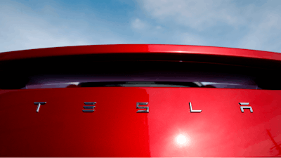 In this April 15, 2018, file photo, the sun shines off the rear deck of a roadster on a Tesla dealer's lot in the south Denver suburb of Littleton, Colo. Electric car producer Tesla says it will build its first factory outside the United States in Shanghai. Tesla says an agreement signed Tuesday, July 10, with a Shanghai city government agency calls for construction to start in the near future.