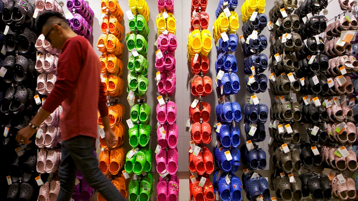 In this April 9, 2010, file photo, Summett Kumar, a Crocs ambassador, works at Crocs store inside the Beverly Center shopping mall in Los Angeles. Crocs Inc. is closing company-owned manufacturing plants in Italy and Mexico by year's end and replacing its chief financial officer. The company announced the outsourcing of additional manufacturing and the closure of a distribution facility in Mexico Tuesday, Aug. 7, 2018, while reporting a second-quarter profit of $30.4 million, or 35 cents per share.