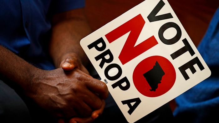 In this Tuesday, July 31, 2018, file photo, people opposing Proposition A listen to a speaker during a rally in Kansas City, Mo. Missouri votes Tuesday, Aug. 7 on a so-called right-to-work law, a voter referendum seeking to ban compulsory union fees in all private-sector workplaces.