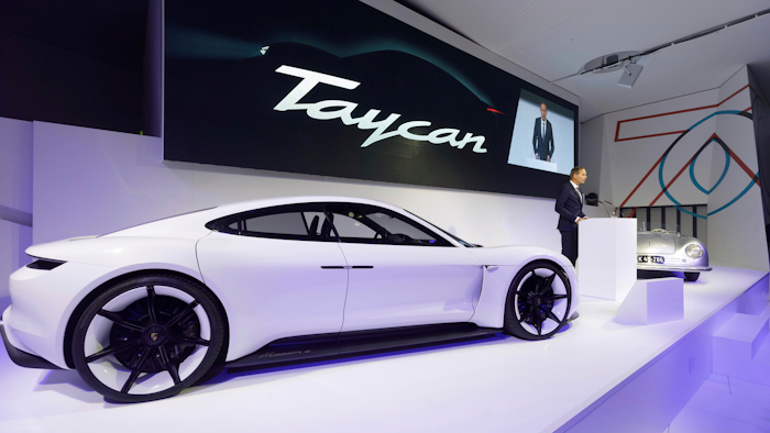 In this Aug. 6, 2018, photo provided by Porsche AG, Oliver Blume, CEO of Porsche AG, speaks next to the Taycan during the ceremonial opening of “70 Years Porsche Sportscar” at the Porsche Museum in Stuttgart, Germany. While Tesla grapples with internal issues like production delays, a sometimes-erratic CEO and a recent about-face on whether to go private, its rivals are moving aggressively into the luxury electric vehicle space. Porsche is taking on Tesla's Model S high performance luxury car with the Taycan, expected to reach the market in late 2019.