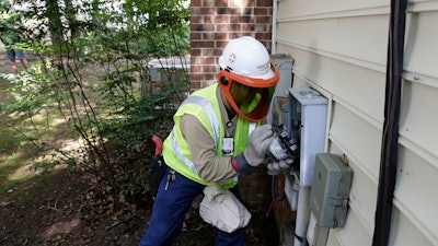 In this photo taken Friday, July 13, 2018 Grid One Solutions employee Spencer Powell installs a new smart meter for Duke Energy Progress at a residence in Raleigh, N.C. Electric utilities are pouring billions of dollars into a race to prevent terrorists or enemy governments from shutting down the power grid while also making the delivery system ready for a world with much more renewable energy.