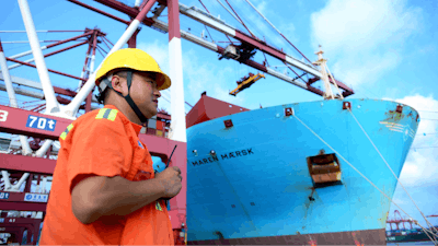 In this Aug. 8, 2018, photo, a worker stands near a container ship at a port in Qingdao in eastern China's Shandong Province. Beijing is responding to U.S. President Donald Trump’s tariff hikes by pressing companies to find more non-U.S. suppliers and customers. But there are few substitutes for the United States as a market and technology supplier.