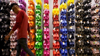 In this April 9, 2010, file photo, Summett Kumar, a Crocs ambassador, works at Crocs store inside the Beverly Center shopping mall in Los Angeles. Crocs Inc. is closing company-owned manufacturing plants in Italy and Mexico by year's end and replacing its chief financial officer. The company announced the outsourcing of additional manufacturing and the closure of a distribution facility in Mexico Tuesday, Aug. 7, 2018, while reporting a second-quarter profit of $30.4 million, or 35 cents per share.