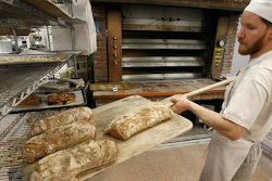 An employee at employee-owned King Arthur Flour Co. in Norwich, Vermont, takes bread from the oven.