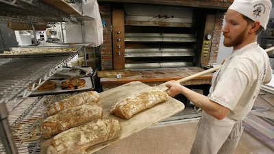 An employee at employee-owned King Arthur Flour Co. in Norwich, Vermont, takes bread from the oven.