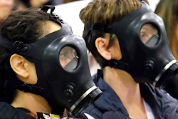 In this Jan. 16, 2016 file photo, protestors wearing gas masks attend a hearing over a gas leak at the southern California Gas Company's Aliso Canyon Storage Facility near the Porter Ranch section of Los Angeles. A tentative settlement has been reached in litigation stemming from a leak at a Los Angeles storage field where a massive methane release forced thousands from their homes three years ago.