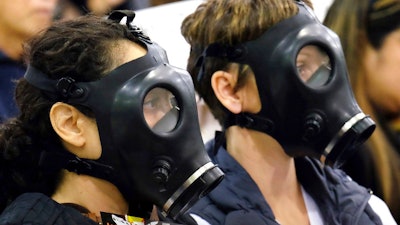 In this Jan. 16, 2016 file photo, protestors wearing gas masks attend a hearing over a gas leak at the southern California Gas Company's Aliso Canyon Storage Facility near the Porter Ranch section of Los Angeles. A tentative settlement has been reached in litigation stemming from a leak at a Los Angeles storage field where a massive methane release forced thousands from their homes three years ago.