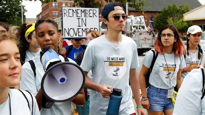 David Hogg, center, a survivor of the school shooting at Marjory Stoneman Douglas High School, in Parkland, Fla., walks in a planned 50-mile march, Thursday, Aug. 23, 2018, in Worcester, Mass. The march, held to call for gun law reforms, began Thursday, in Worcester, and is scheduled to end Sunday, Aug. 26, in Springfield, Mass., at the headquarters of gun manufacturer Smith & Wesson.
