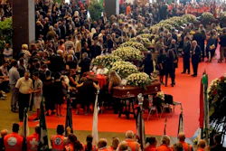 People gather for a funeral service for some of the victims of a collapsed highway bridge, in Genoa's exhibition center Fiera di Genova, Italy, Saturday, Aug. 18, 2018. Saturday has been declared a national day of mourning in Italy and includes a state funeral at the industrial port city's fair grounds for those who plunged to their deaths as the 45-meter (150-foot) tall Morandi Bridge gave way Tuesday.