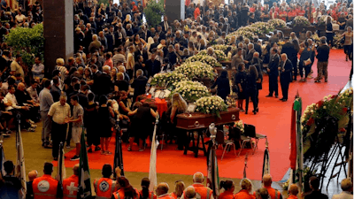 People gather for a funeral service for some of the victims of a collapsed highway bridge, in Genoa's exhibition center Fiera di Genova, Italy, Saturday, Aug. 18, 2018. Saturday has been declared a national day of mourning in Italy and includes a state funeral at the industrial port city's fair grounds for those who plunged to their deaths as the 45-meter (150-foot) tall Morandi Bridge gave way Tuesday.