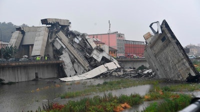 Rescuers work among the rubble of the collapsed Morandi highway bridge in Genoa, northern Italy, Tuesday, Aug. 14, 2018. A large section of the bridge collapsed over an industrial area in the Italian city of Genova during a sudden and violent storm, leaving vehicles crushed in rubble below.