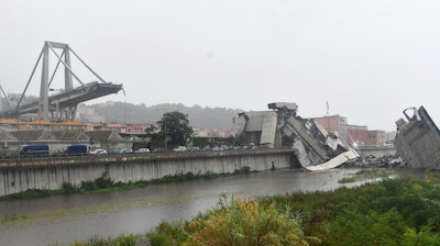 A view of the collapsed Morandi highway bridge in Genoa, northern Italy, Tuesday, Aug. 14, 2018. A large section of the bridge collapsed over an industrial area in the Italian city of Genova during a sudden and violent storm, leaving vehicles crushed in rubble below.