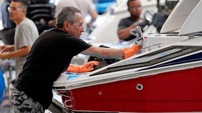In this July 11, 2018 file photo, workers put finishing touches on boat exteriors at Regal Marine Industries in Orlando, Fla. American boat makers are getting pummeled on multiple fronts by tariffs and stand to be among the industries hardest-hit by the escalating trade war.