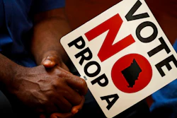In this Tuesday, July 31, 2018, file photo, people opposing Proposition A listen to a speaker during a rally in Kansas City, Mo. Missouri votes Tuesday, Aug. 7 on a so-called right-to-work law, a voter referendum seeking to ban compulsory union fees in all private-sector workplaces.
