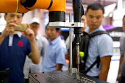 In this Aug. 15, 2018, photo, visitors look at a manufacturing robot from Chinese robot maker Aubo Robotics at the World Robot Conference in Beijing, China. The United States and China imposed more tariff hikes on billions of dollars of each other's automobiles, factory machinery and other goods Thursday, Aug. 23, 2018, in an escalation of a battle over Beijing's technology policy that companies worry will chill global economic growth.