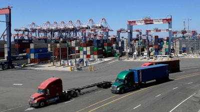 In this Wednesday, Aug. 22, 2018, photo trucks travel along a loading dock at the Port of Long Beach in Long Beach, Calif. Between them, the California ports of Los Angeles and Long Beach account for a large amount of the seaborne goods that the United States imports from China, and the prospect of a widening trade war between the global giants has port executives and longshoremen worried.