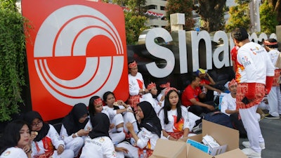 In this Aug. 5, 2018, photo, students sit in front of building that houses the headquarters of Sinarmas Group, one of Indonesia's largest palm oil company, in Jakarta, Indonesia. The main global group for certifying sustainable wood has suspended plans to give its influential endorsement to Indonesian paper giant Sinarmas after revelations it cut down tropical forests and used an opaque corporate structure to hide its activities.