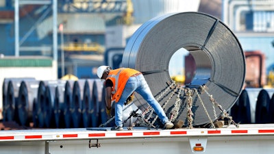 In this July 25, 2018, photo a truck driver chains down a roll of steel to his flatbed at the NUCOR Steel Gallatin plant in Ghent, Ky. The rolls, weighing as much as 20 tons, are transported one at a time. On Wednesday, Aug. 15, the Federal Reserve reports on U.S. industrial production for July.