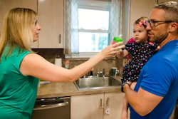 In this Aug. 1, 2018 photo, Lauren Woehr hands her 16-month-old daughter Caroline, held by her husband Dan McDowell, a cup filled with bottled water at their home in Horsham, Pa. In Horsham and surrounding towns in eastern Pennsylvania, and at other sites around the United States, the foams once used routinely in firefighting training at military bases contained per-and polyfluoroalkyl substances, or PFAS. EPA testing between 2013 and 2015 found significant amounts of PFAS in public water supplies in 33 U.S. states.
